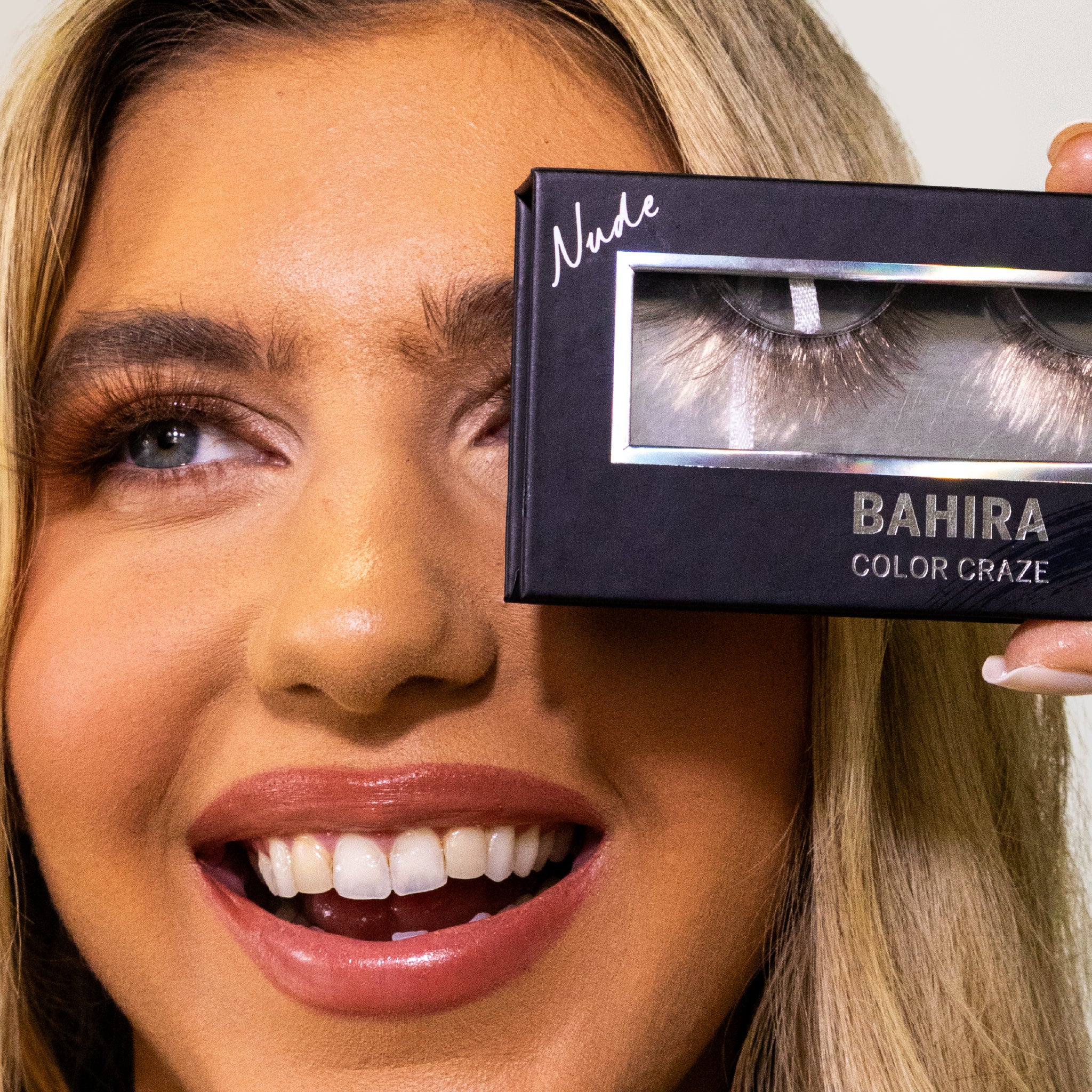 Smiling model holding a Bahira Nude lash box